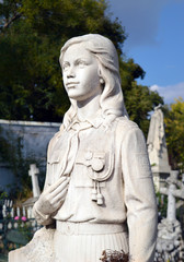 Fototapeta na wymiar Statue of young girl in Pioneer uniform on grave in Bucharest