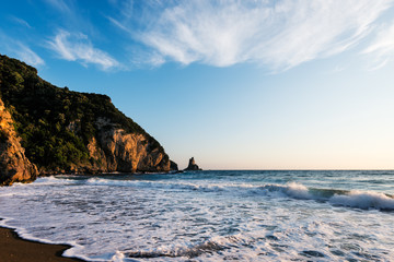 Foamy water  on sandy beach shore at sunset, Agios Gordios beach, Corfu, Greece.