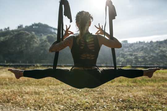Spain, Villaviciosa, woman practicing aerial yoga outdoors