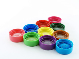 close-up group of colorful plastic bottle lids of poster color arrange to triangle formed isolated on white background, learning shapes for children