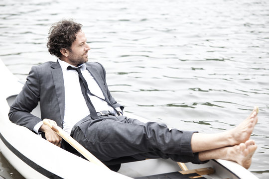 Germany, Rur Reservoir, businessman relaxing in canoe