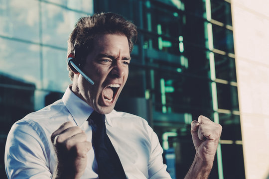 Excited businessman with clenched fists screaming outside office building