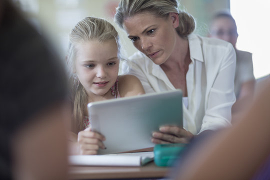 Teacher and schoolgirl with digital tablet in classroom