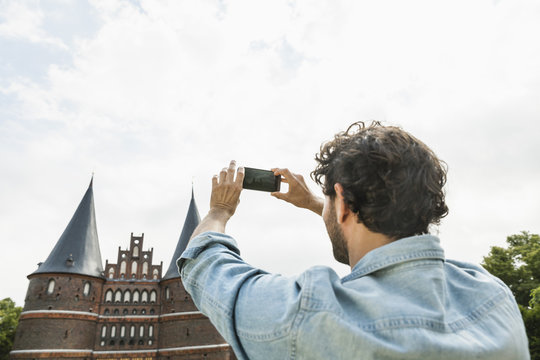 Germany, Luebeck, man taking picture in front of the Holsten Gate