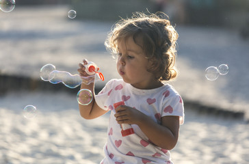 Little girl making soap bubbles at playground