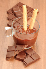 cup of liquid chocolate and chocolate pieces in dark wooden tabl