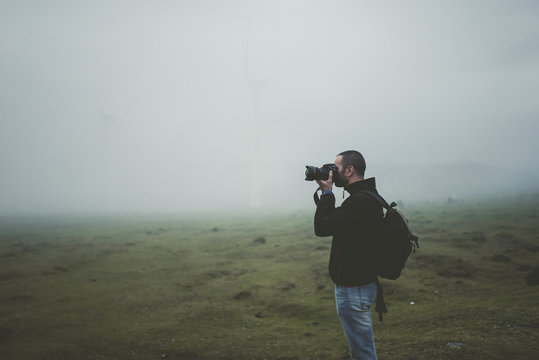 Spain, Ortigueira, photographer taking pictures on a meadow with fog