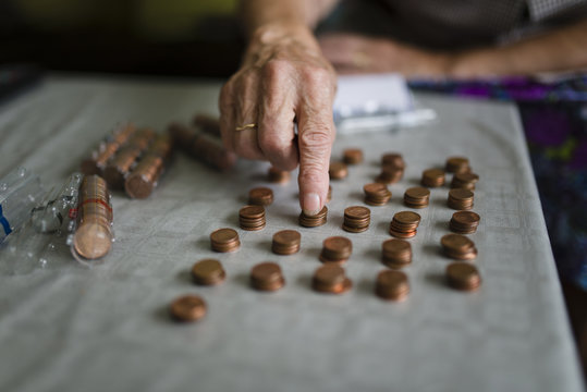 Elderly woman counting money, making stacks of Euro cents