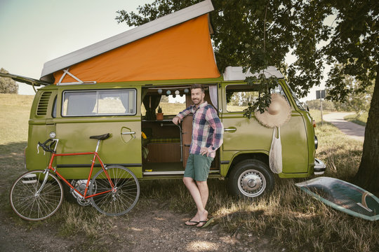 Smiling man in front of van in the nature