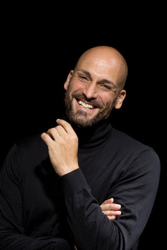 Portrait of laughing man wearing black turtleneck in front of black background