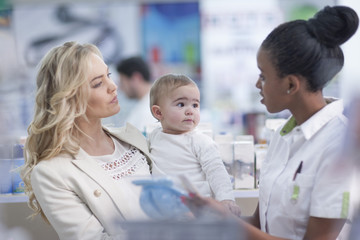 Pharmacist assisting client with baby in drugstore