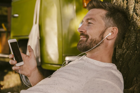 Man listening to music at tree in front of van