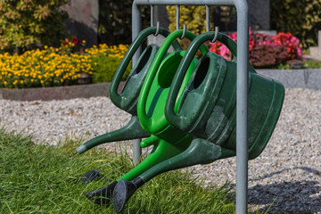 Drei grüne Gießkannen am Friedhof