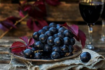 Black table grapes on plate with black wine
