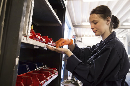Young woman working in repair garage, searching spare parts