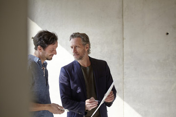 Two men on construction site discussing document