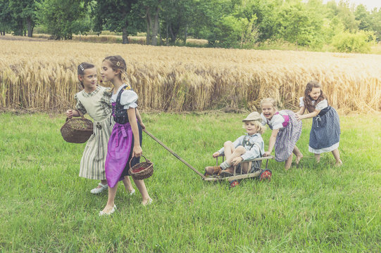 Germany, Saxony, five children with trolley on a meadow