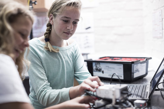 Two schoolgirls with laptop in robotics class