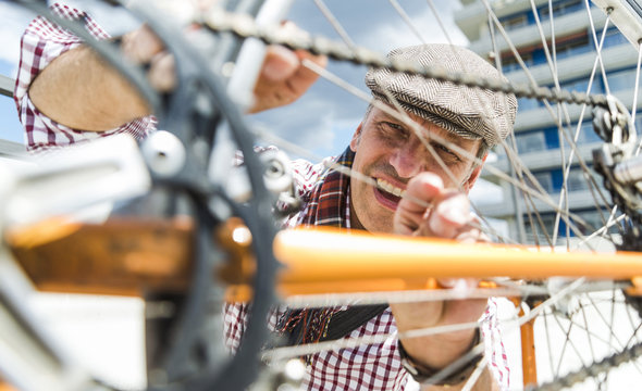 Mature man repairing bicycle leaning