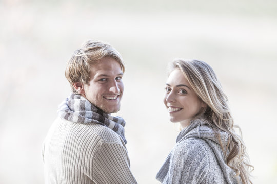 Portrait of smiling young couple looking over their shoulders