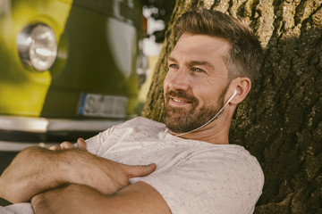 Man listening to music at tree in front of van
