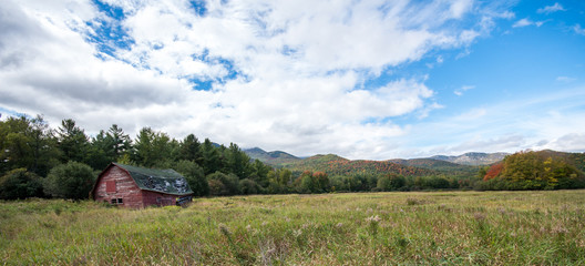 Old run down barn with fall color in the Adirondacks in the background