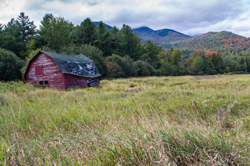Old run down barn with fall color in the Adirondacks in the background