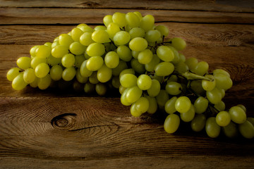 Bunch of green grapes on a dark wooden background. Selective focus. The toning 