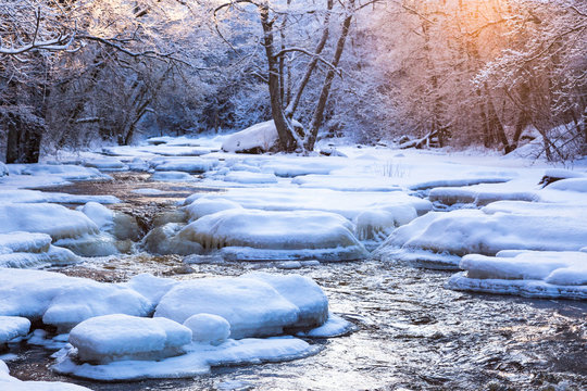 Winter landscape by a river in the sunset