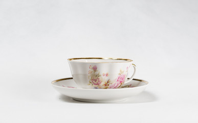 Antique porcelain tea cup with floral painting on white backgrou