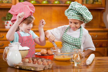 two happy children preparing eggs for cookies in the kitchen