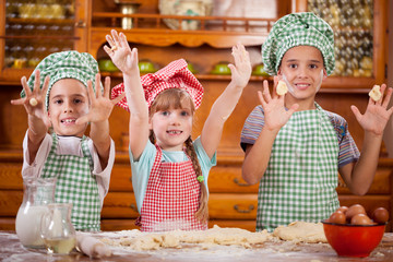 three funny young child  play with a dough in the kitchen