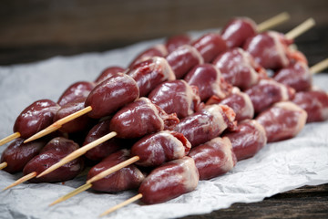 Ready to cook Duck Heart stringed on skewers BBQ on crumpled paper. background