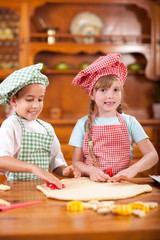 Two beautiful caucasian child making a cake, smiling happily,