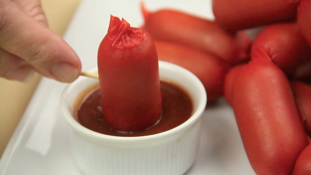 Australian frankfurter called a cheerio on a toothpick being dipped into ketchup then falls over in sauce.