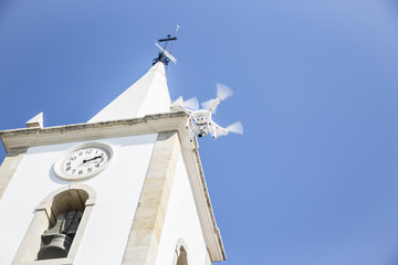 white drone flying on a blue sky next to a white church