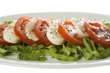 Italian salad - Caprese salad, tomato and mozzarella with spices, served on a white plate. Isolated on white.