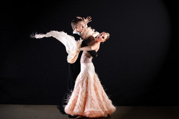 dancers in ballroom against on black