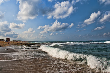 In the morning warm little waves rolled on a wild beach and  in the sky slowly floating clouds