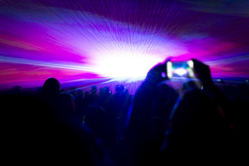 Laser show party rays in front of smartphone filming video. Best visual show with a crowd silhouette and great laser rays for e.g. an illustration background of an invitation flyer