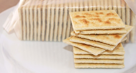 Stack of crispy salted crackers on a plate to be enjoyed plain or with a topping
