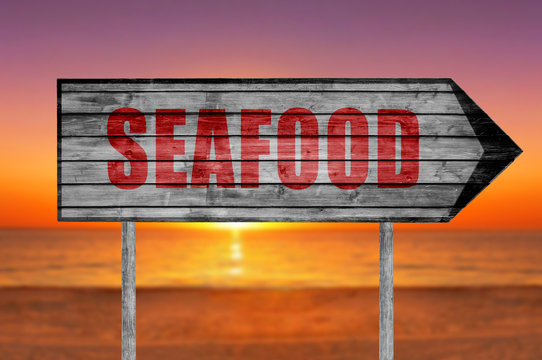 Red Seafood wooden sign with a beach on background