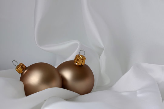 Twee kerstballen op een witte doek
