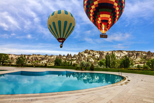 Hot air balloons over swimming pool, Cappadocia, Turkey
