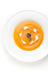 Pumpkin soup in a white plate. Top view, vertical