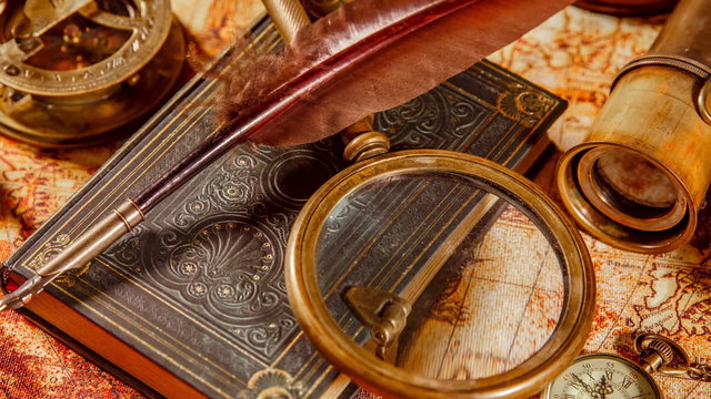 Vintage book, compass, telescope and a pocket watch lying on ancient world map in 1565.