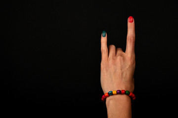 Hand with devil horns and colorful beads isolated on black