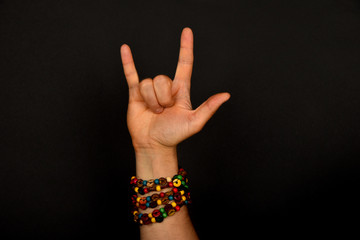 Hand with devil horns and colorful beads isolated on black