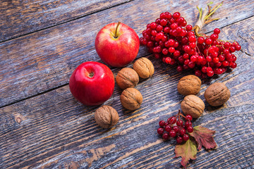 Autumn leaves, nuts, apples, viburnum on a wooden background