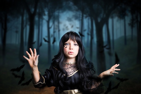 kleines Mädchen als Hexe verkleidet, im Wald mit vielen Fledermäusen